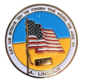 coin with American flag with an Abe Lincoln quote reading "let us strive on to finish the work are in!"